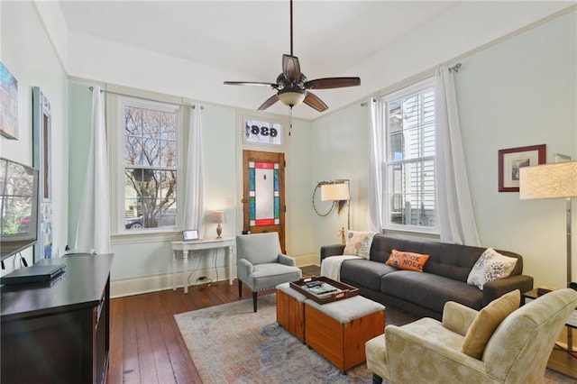 living room with baseboards, a ceiling fan, and dark wood-style flooring