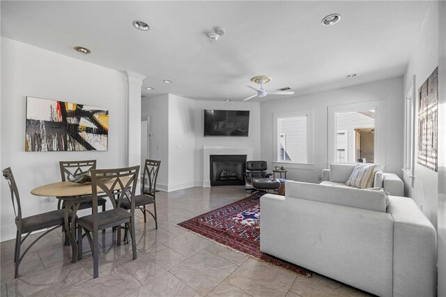 living area featuring a fireplace, decorative columns, recessed lighting, a ceiling fan, and baseboards