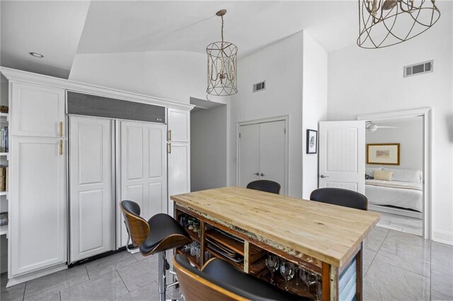 dining room featuring a ceiling fan, visible vents, vaulted ceiling, and light tile patterned flooring