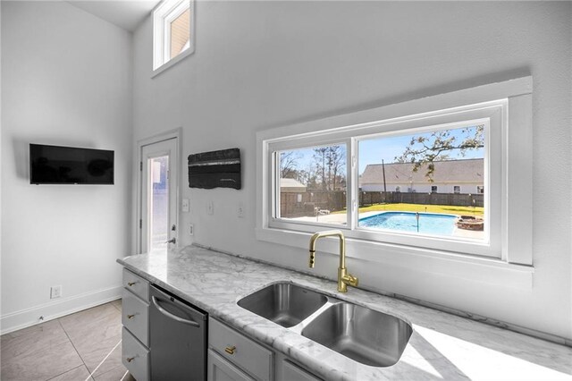 kitchen featuring plenty of natural light, dishwasher, a sink, and light stone countertops