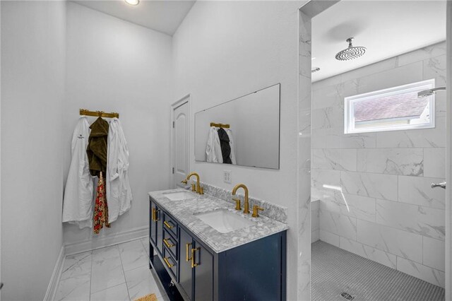 bathroom featuring marble finish floor, tiled shower, and a sink