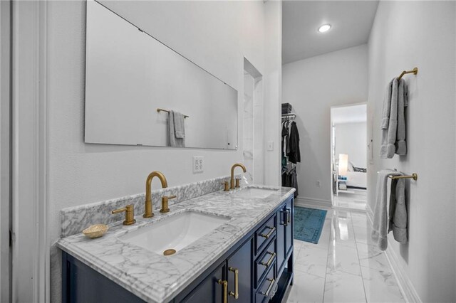 bathroom featuring marble finish floor, a sink, baseboards, and double vanity