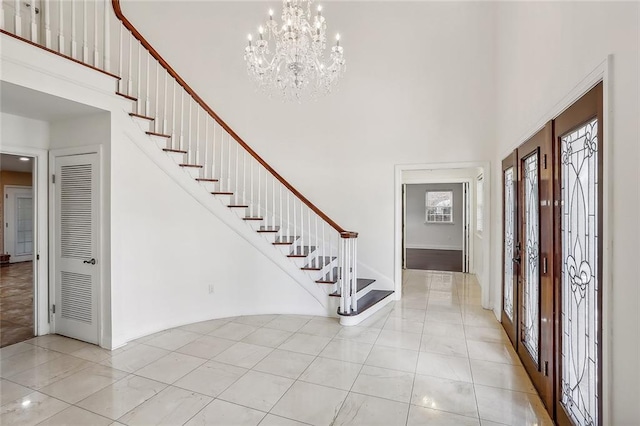 foyer featuring an inviting chandelier, stairway, and a high ceiling