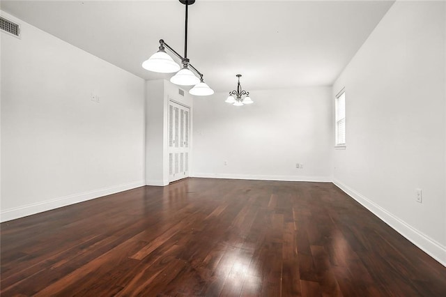 unfurnished room featuring a chandelier, baseboards, and dark wood finished floors