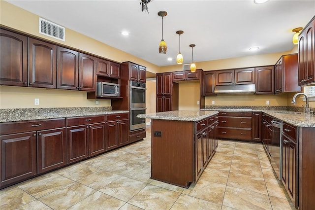 kitchen with light stone counters, visible vents, a kitchen island, a sink, and appliances with stainless steel finishes