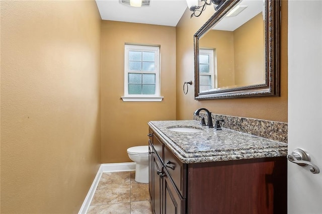 half bathroom with baseboards, toilet, and vanity