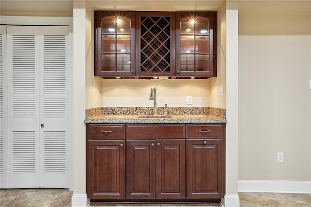 bar with indoor wet bar, light tile patterned floors, baseboards, and a sink