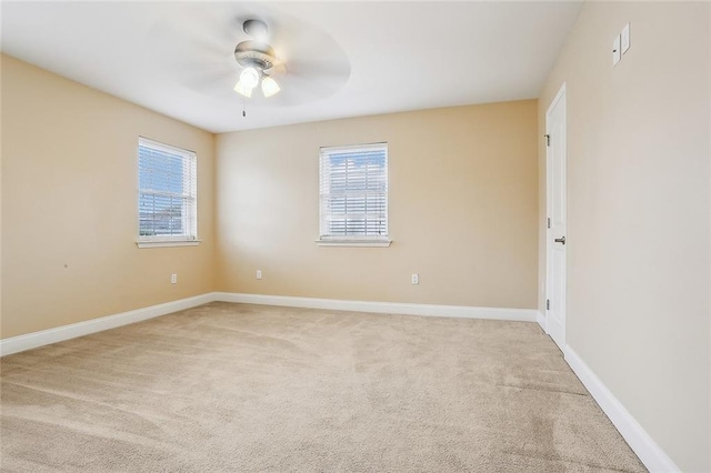 spare room with plenty of natural light, light colored carpet, and baseboards