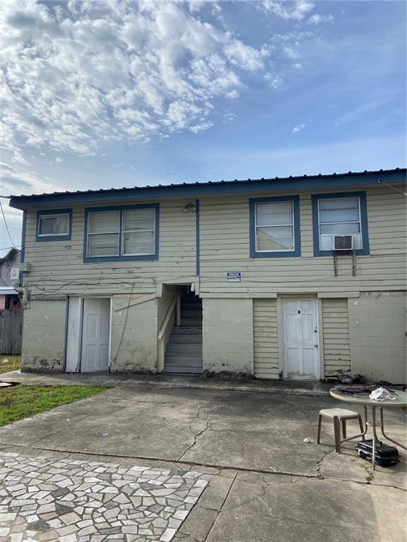 rear view of house featuring cooling unit, metal roof, a patio, and stairs