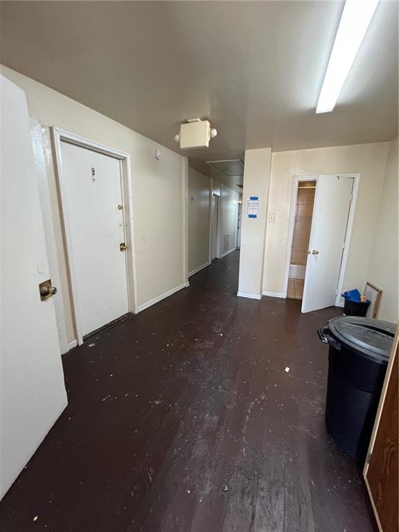 unfurnished room with dark wood-type flooring and baseboards