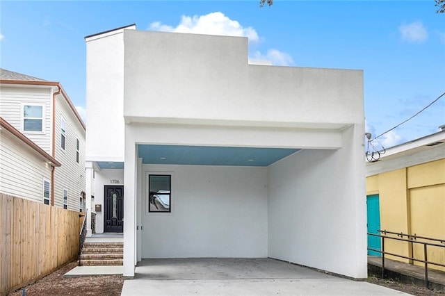 rear view of property featuring stucco siding, a carport, and fence