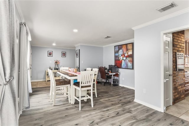 dining area featuring visible vents, crown molding, baseboards, and wood finished floors