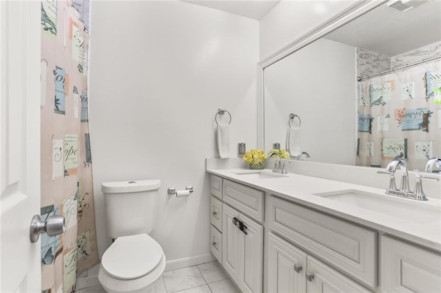 bathroom with baseboards, a sink, toilet, and double vanity