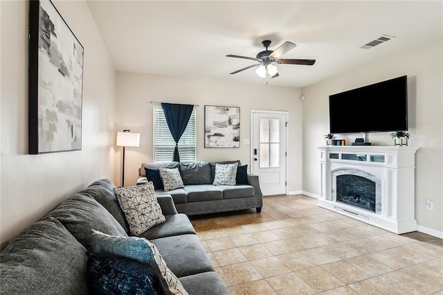 living area featuring a fireplace, light tile patterned floors, visible vents, ceiling fan, and baseboards