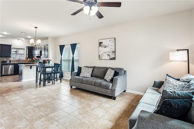 living area with light tile patterned floors, visible vents, baseboards, and ceiling fan with notable chandelier