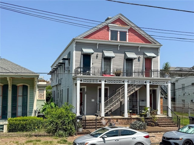 victorian home with covered porch, a fenced front yard, and stairs