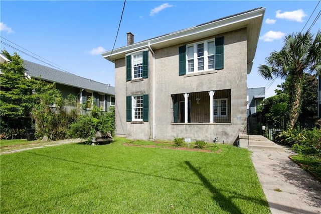 view of front of property with a front yard, a chimney, and stucco siding