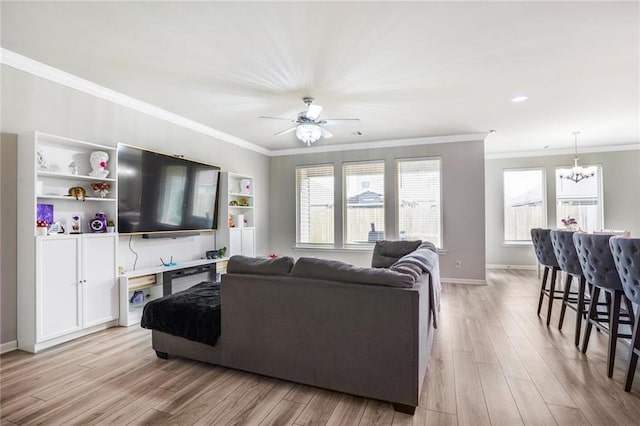 living room with baseboards, ceiling fan with notable chandelier, light wood-style flooring, and crown molding