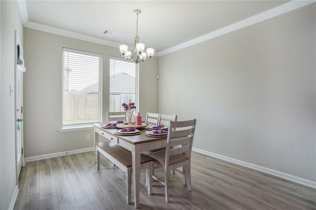 dining space featuring crown molding, light wood-style flooring, and a notable chandelier