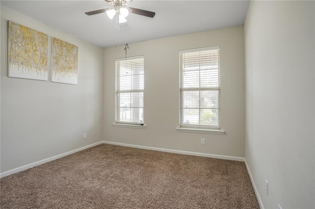 carpeted spare room featuring baseboards and a ceiling fan