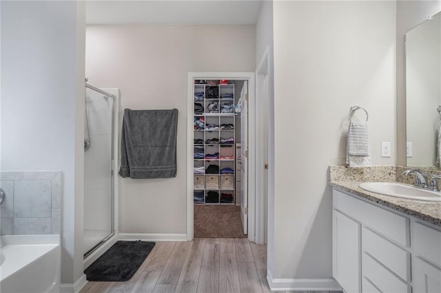 bathroom with a spacious closet, a stall shower, wood finished floors, and vanity