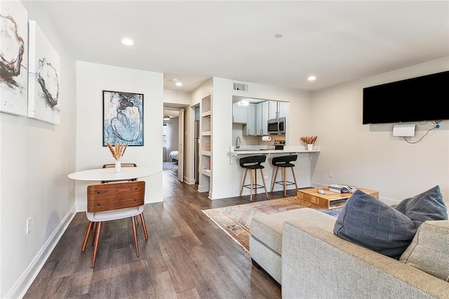 living room featuring recessed lighting, dark wood finished floors, visible vents, and baseboards