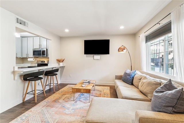 living room featuring recessed lighting, dark wood finished floors, visible vents, and baseboards