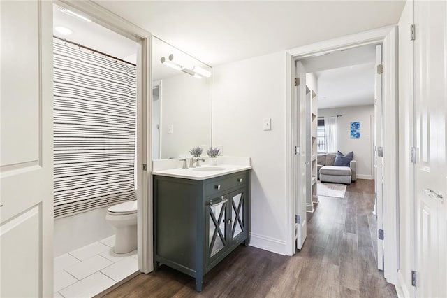 full bath with toilet, wood finished floors, vanity, and baseboards