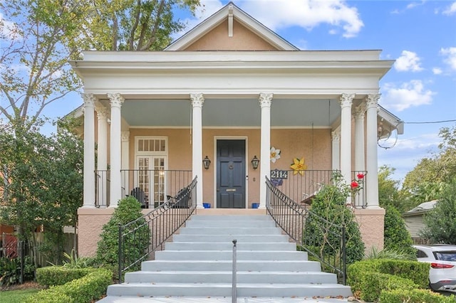 greek revival house featuring a porch and stucco siding