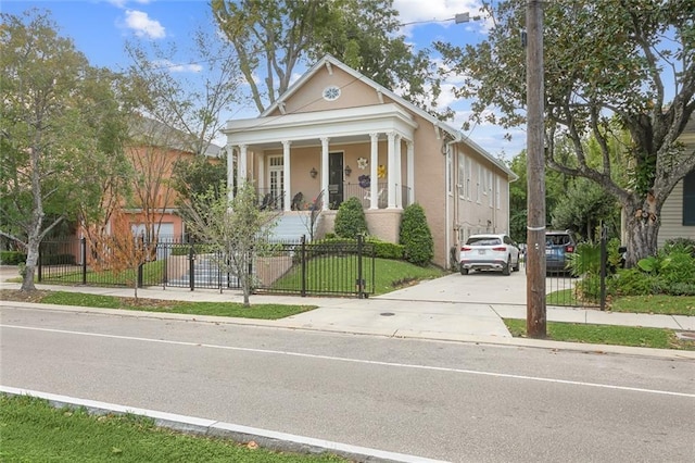 neoclassical / greek revival house with covered porch, a fenced front yard, and stucco siding