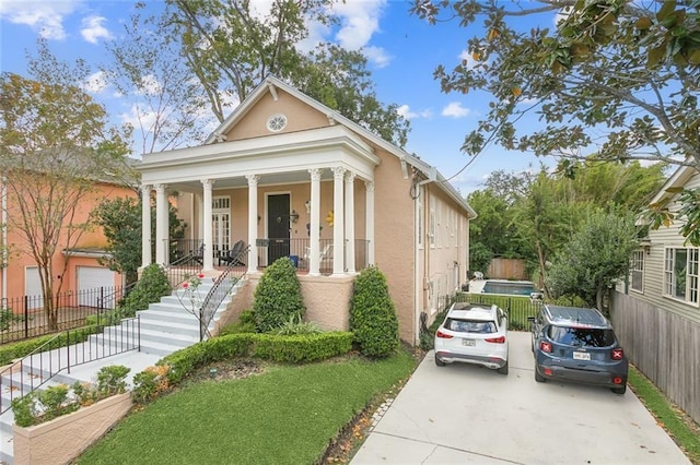 neoclassical / greek revival house with covered porch, fence, and stucco siding