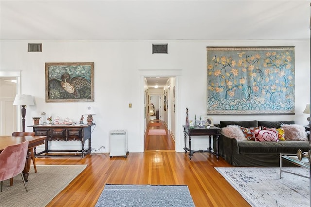 living area with visible vents and wood finished floors