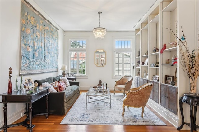 living area featuring an inviting chandelier, baseboards, and wood finished floors