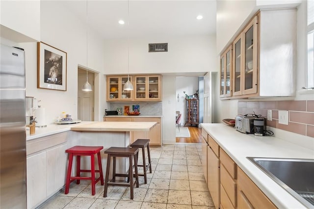 kitchen with a kitchen bar, light countertops, visible vents, and decorative backsplash