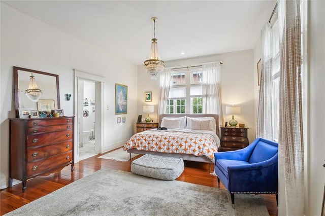 bedroom with an inviting chandelier, wood finished floors, and baseboards