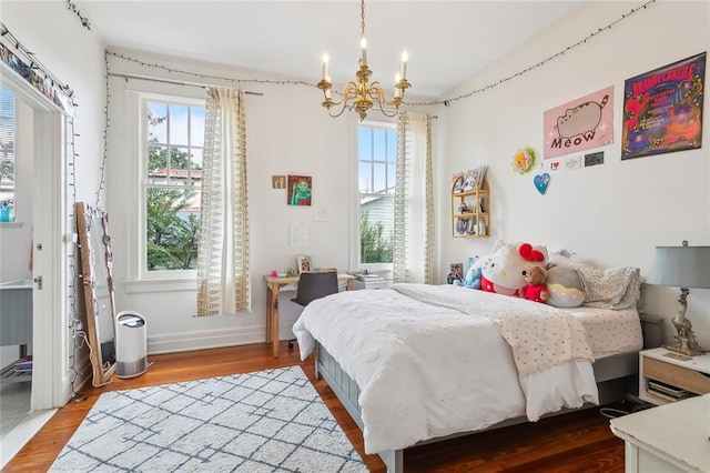 bedroom featuring baseboards, an inviting chandelier, and wood finished floors