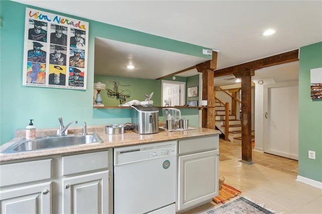 kitchen with recessed lighting, light countertops, white cabinetry, white dishwasher, and a sink