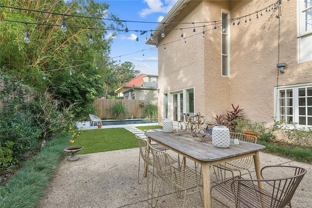 view of patio with outdoor dining space, fence, a fenced in pool, and french doors