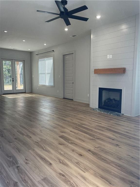 unfurnished living room featuring light wood finished floors, baseboards, french doors, a fireplace, and recessed lighting