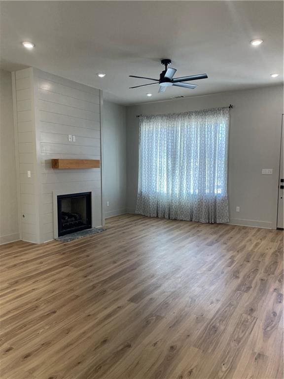 unfurnished living room featuring a large fireplace, a ceiling fan, wood finished floors, and recessed lighting