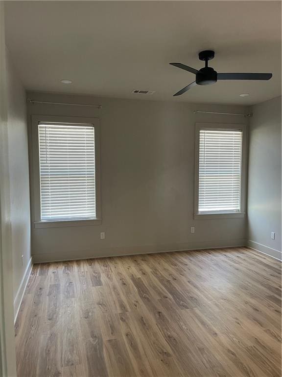 spare room with baseboards, visible vents, ceiling fan, and light wood finished floors