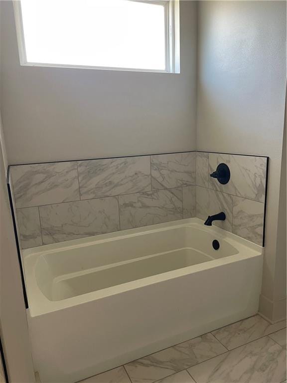 bathroom featuring marble finish floor and a bath