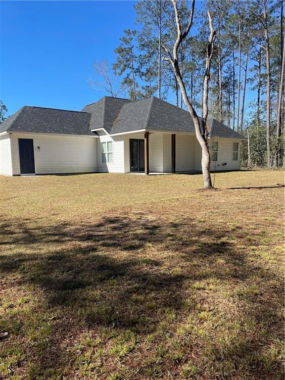 view of front facade with a front yard and roof with shingles