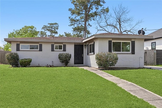 single story home featuring a front yard, brick siding, and fence