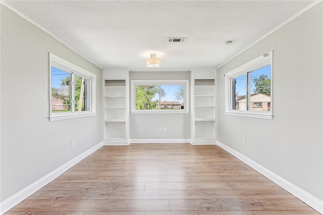 unfurnished room with light wood-type flooring, built in features, and baseboards