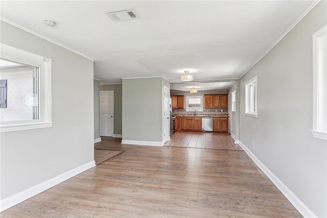 unfurnished living room featuring a sink, visible vents, baseboards, light wood-style floors, and crown molding