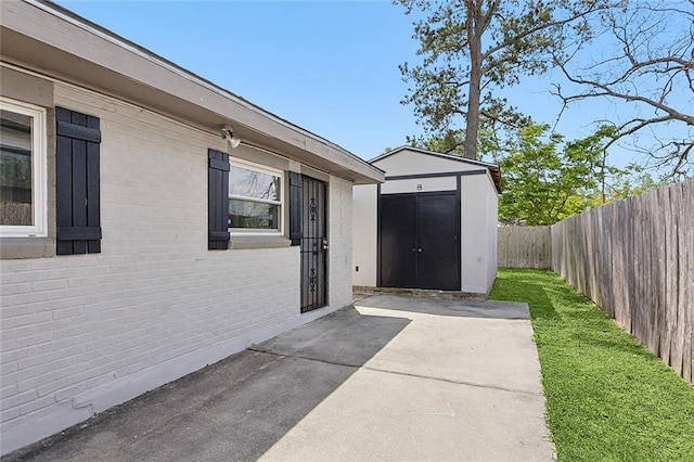 doorway to property with brick siding, a patio area, and fence