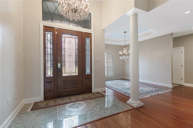 entryway with decorative columns, baseboards, a notable chandelier, and wood finished floors