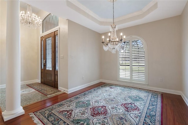 entrance foyer featuring dark wood-style floors, a tray ceiling, baseboards, and an inviting chandelier