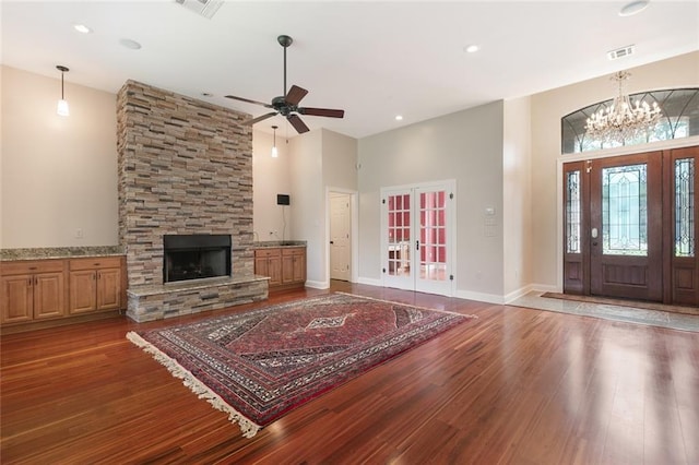 living room with visible vents, a stone fireplace, a high ceiling, and wood finished floors